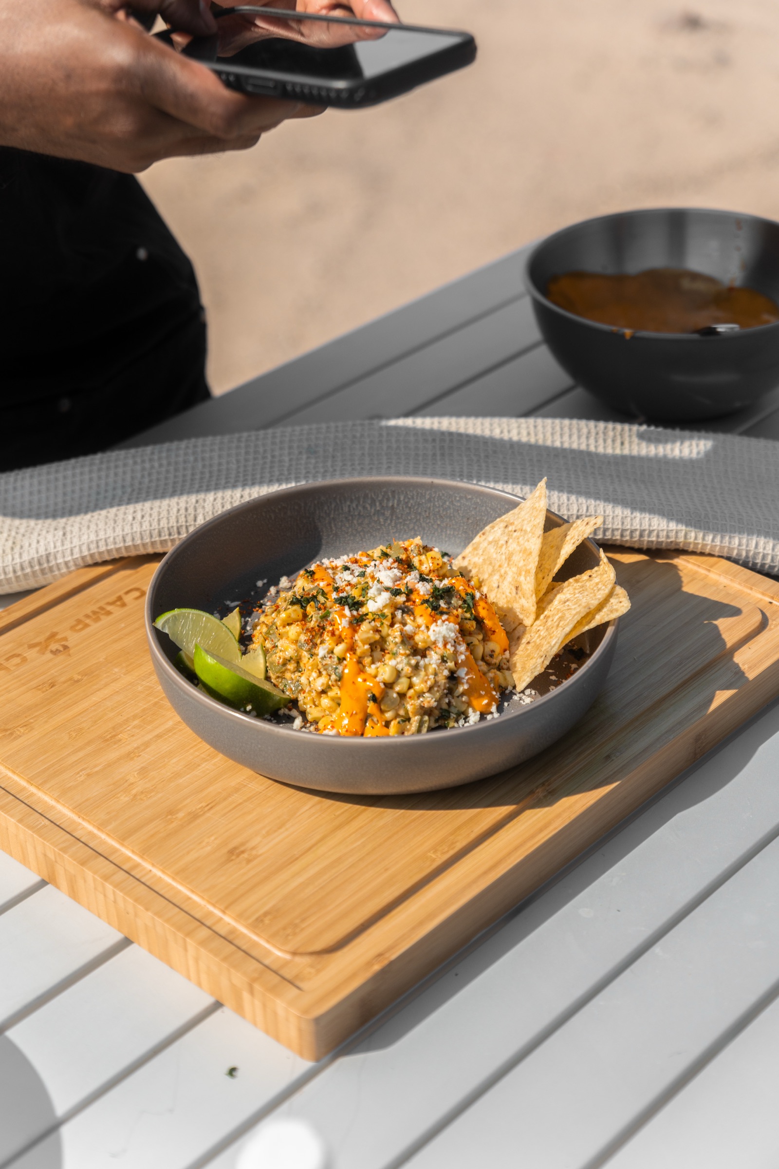 A finished bowl of street corn photographed on a camp table