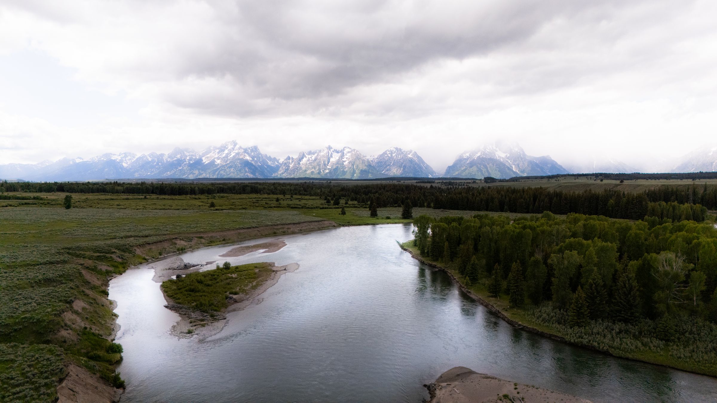 The Snake River winding beneath the Teton range under low clouds